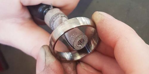 Von unseren Goldschmieden wird der Ring versäubert. Dies bedeutet, dass er mit Schmirgelwalzen verschiedener Körnung bearbeitet wird. Hierdurch werden die entstandenen Drehrillen entfernt.